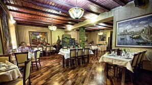 A restaurant with wooden flooring, tables set with white tablecloths, and hanging chandeliers. - Hotel Gaja (Poznan)