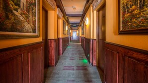 A hotel corridor with wooden paneling, framed artwork on the walls, and a carpeted floor. - Hotel Gaja (Poznan)