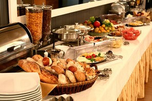 Un bufé con distintos alimentos, entre ellos pan, frutas y ensaladas.