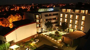 Un hotel con piscina, sillas de descanso y un patio bien iluminado.