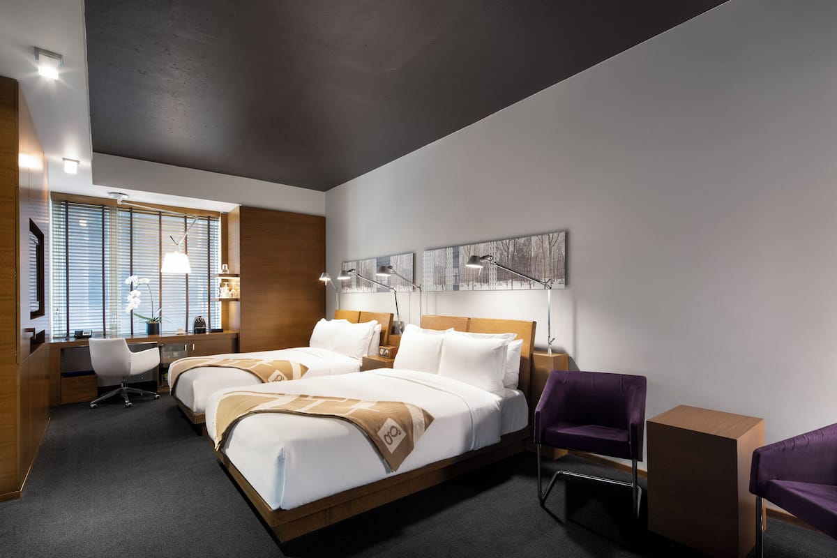 Quarto de hotel moderno com uma cama grande, uma escrivaninha e uma cadeira.