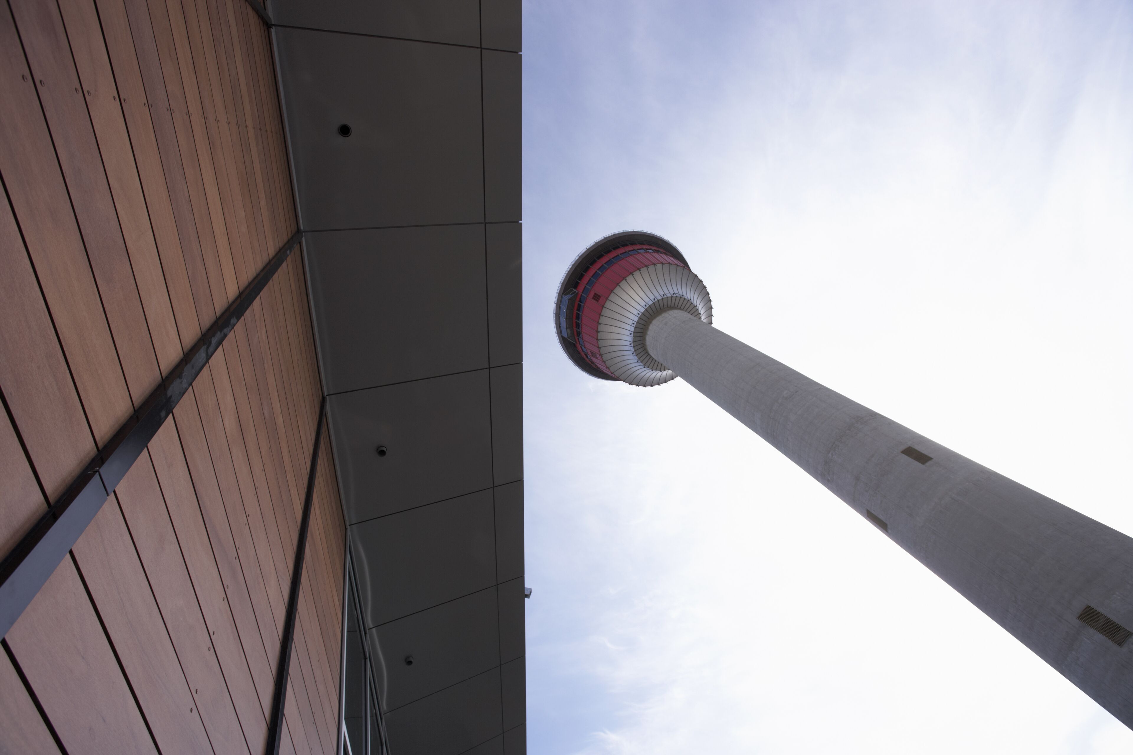 A tall tower with a cylindrical shape and a red and white stripe near the top, viewed from a low angle looking up.