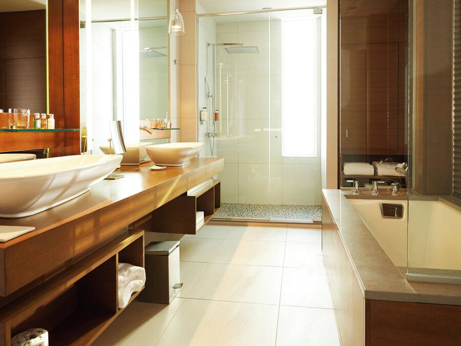 Ein modernes Badezimmer mit einem großen Spiegel, zwei Waschbecken, einer Duschkabine aus Glas und einer begehbaren Dusche.