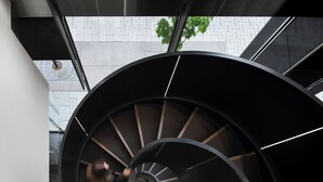 A modern spiral staircase with a metallic finish and a geometric pattern on the wall behind it. - Hotel Le Germain Calgary (Calgary)