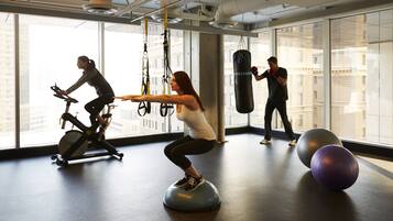Un gimnasio con equipo de ejercicio, ventanas amplias y un saco de boxeo.