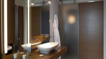 A modern bathroom with a large mirror, a vessel sink, and a towel hanging on the wall.