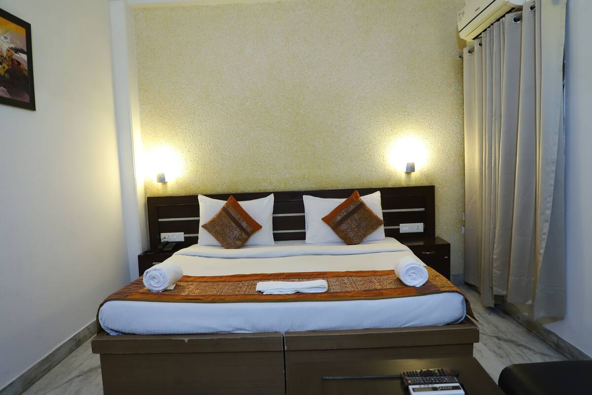 A neatly made bed with a brown headboard, two bedside lamps, and a remote control on the nightstand.