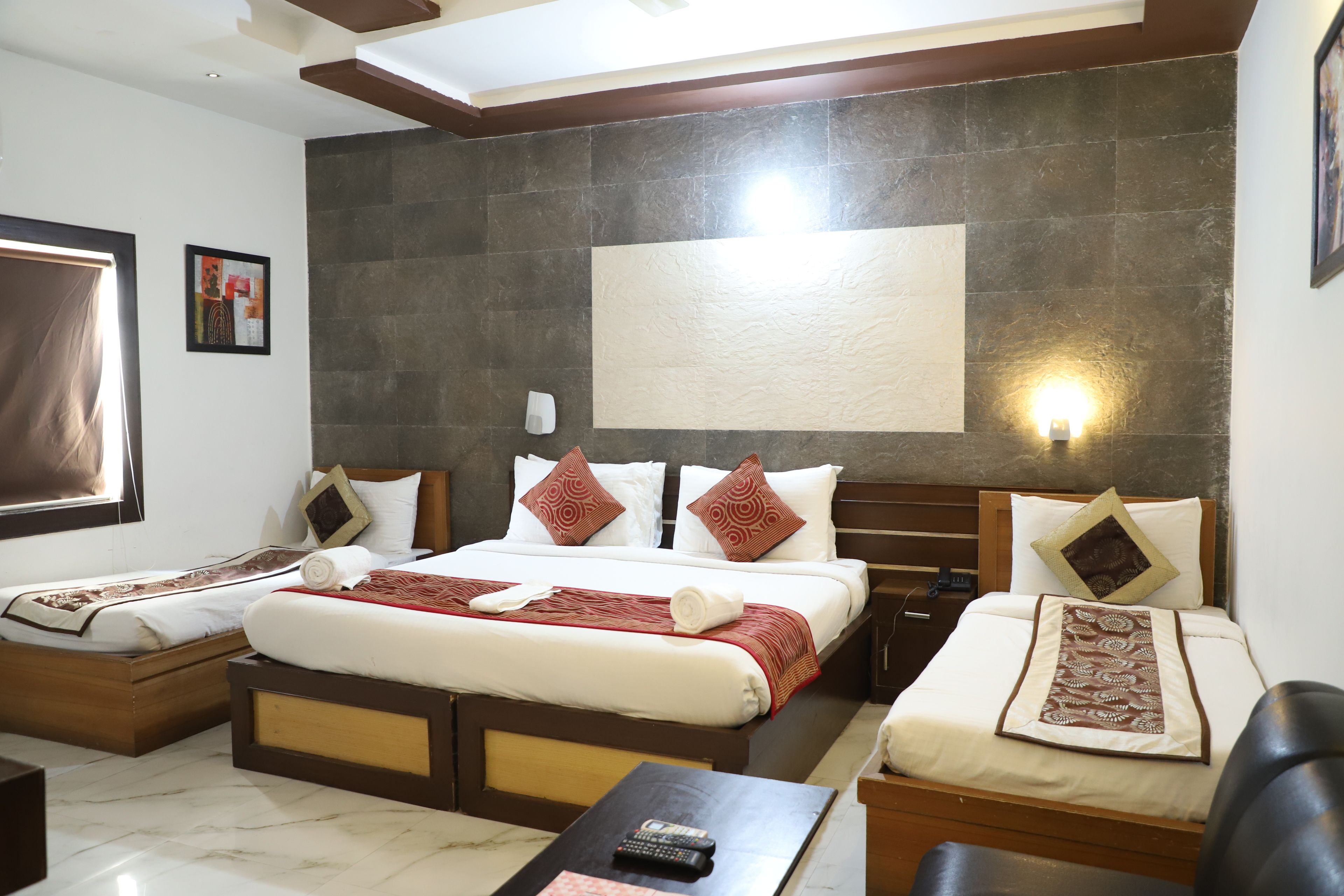 Une chambre d’hôtel avec un grand lit, deux petits lits, un bureau et une télévision.