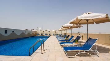 Alberca al aire libre, sombrillas en la alberca y camastros