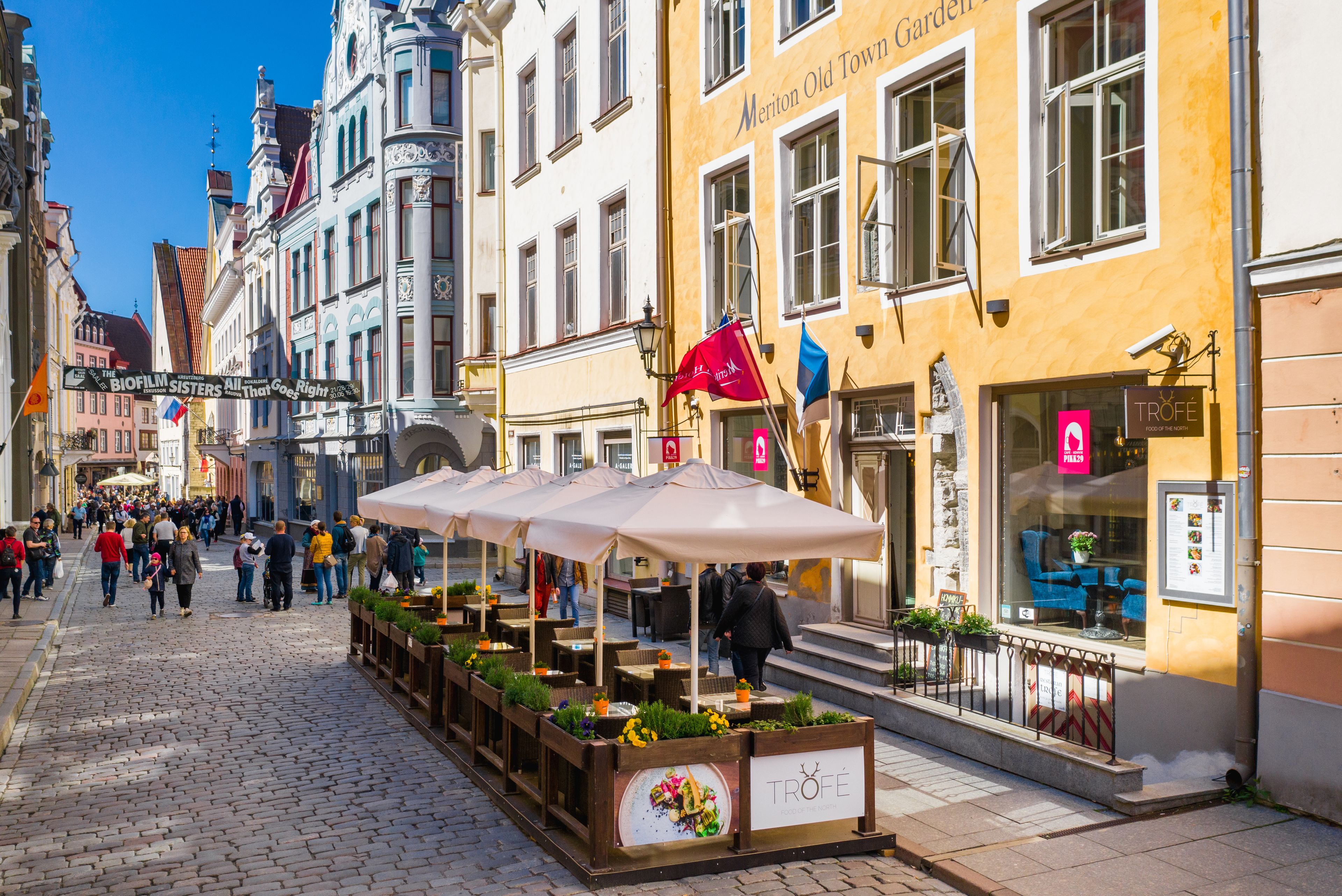 A cobblestone street with outdoor seating areas and a variety of shops.