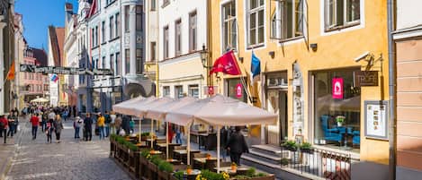A cobblestone street with outdoor seating areas and a variety of shops.