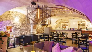 Un intérieur avec des murs en pierre, un espace bar et des coins salon.