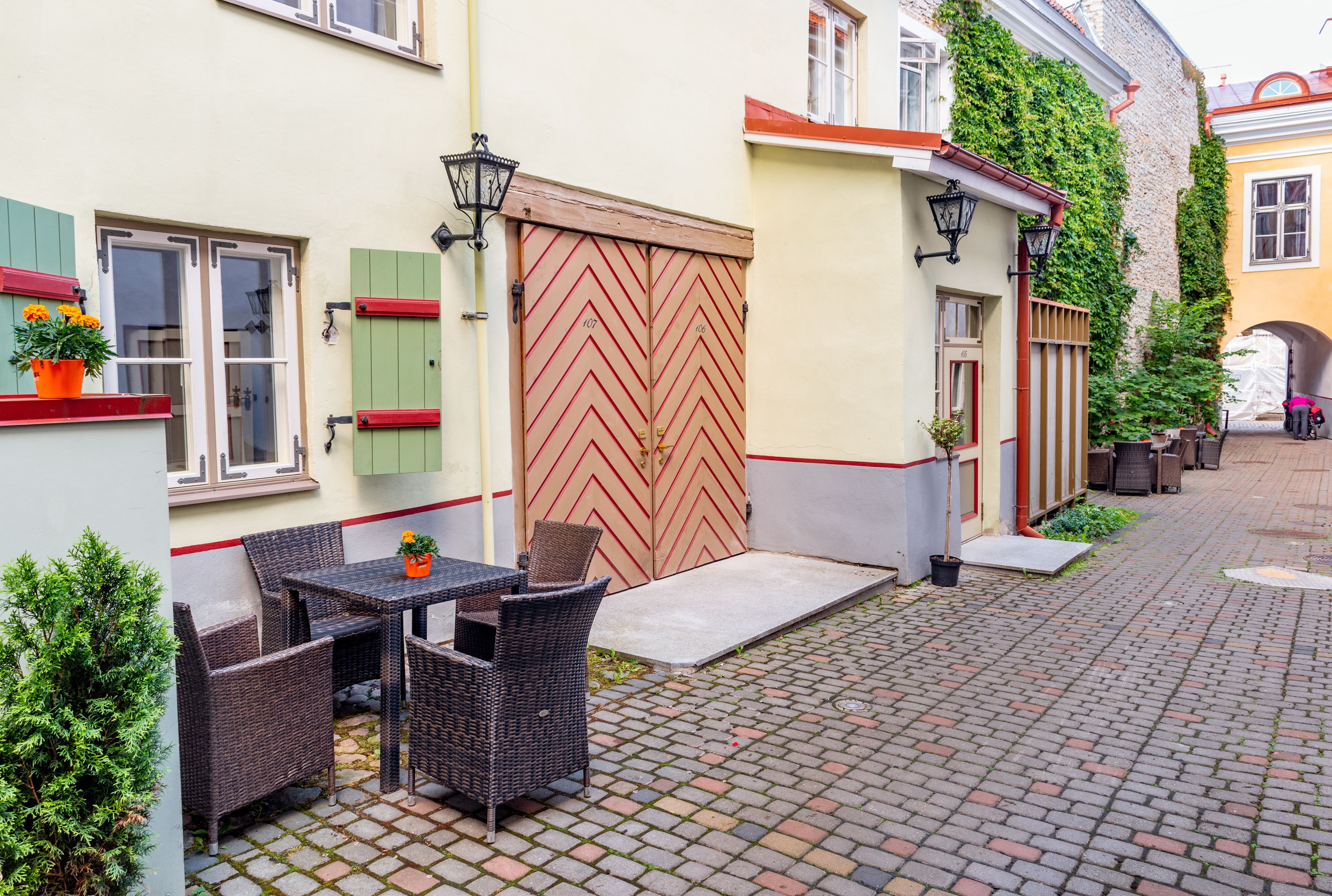 A courtyard with wicker furniture, a wooden gate, and potted plants.
