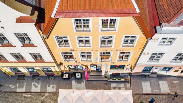 Un hôtel à la façade jaune, doté de nombreuses fenêtres et d’un toit recouvert de tuiles.