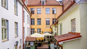 Une ruelle étroite où se trouve un café doté d’une terrasse et de parasols.