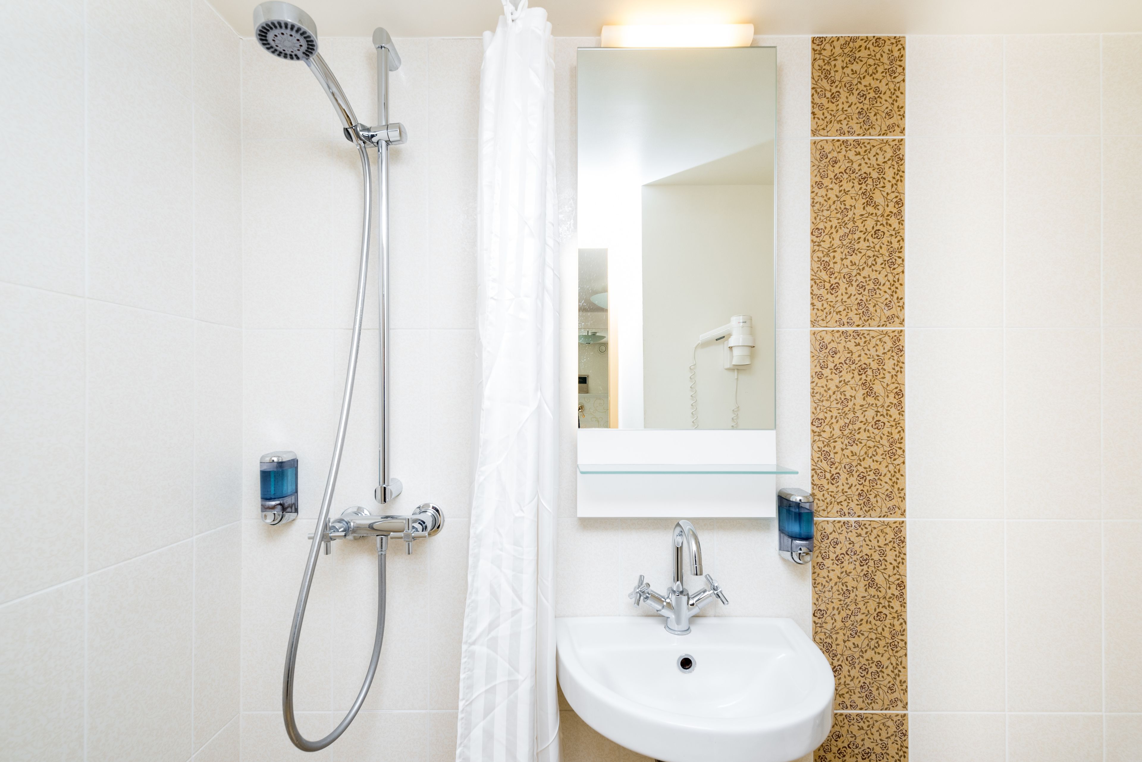 Een badkamer met een douche, wastafel en spiegel.