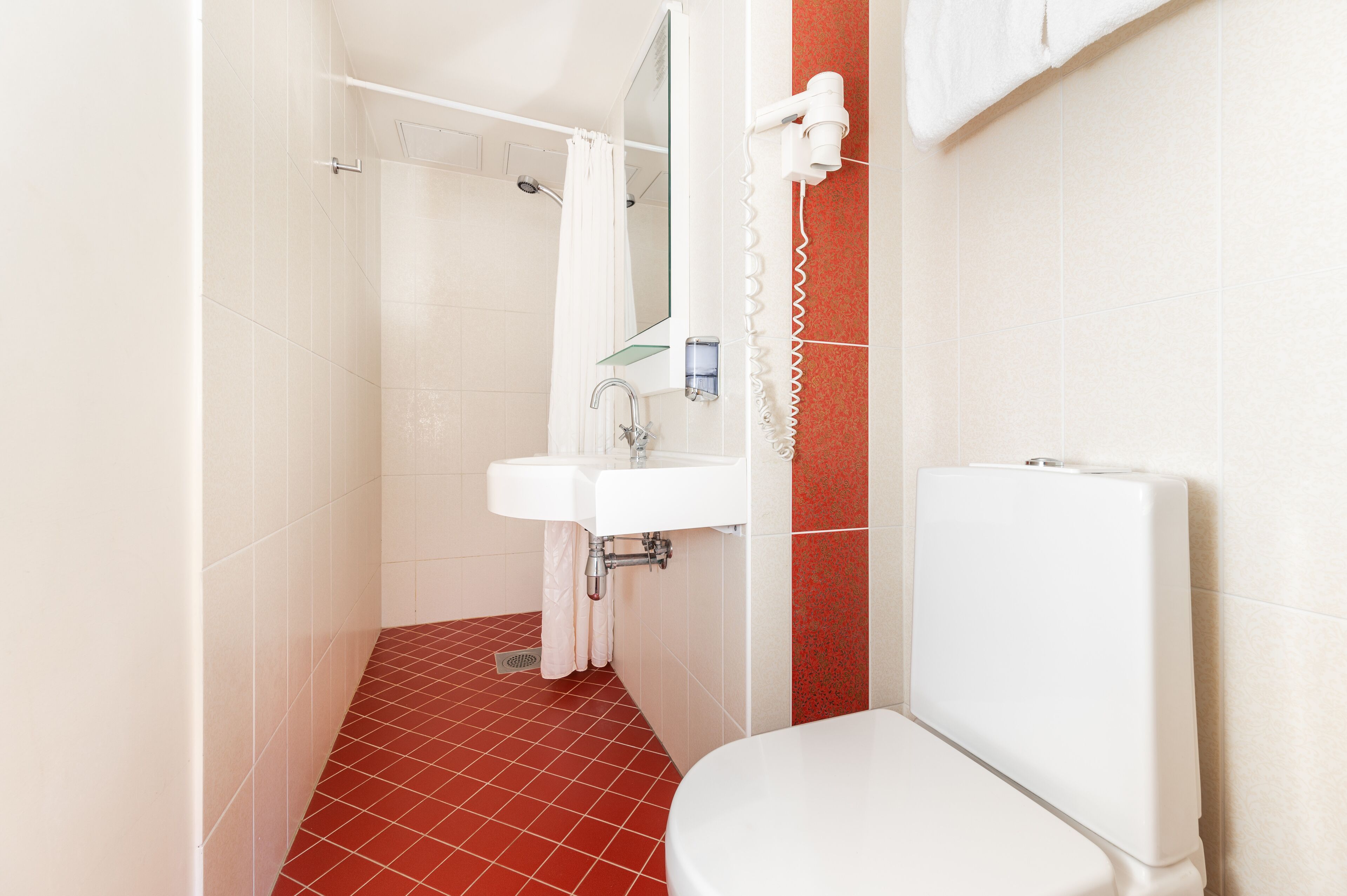 A bathroom with a toilet, sink, and shower area.