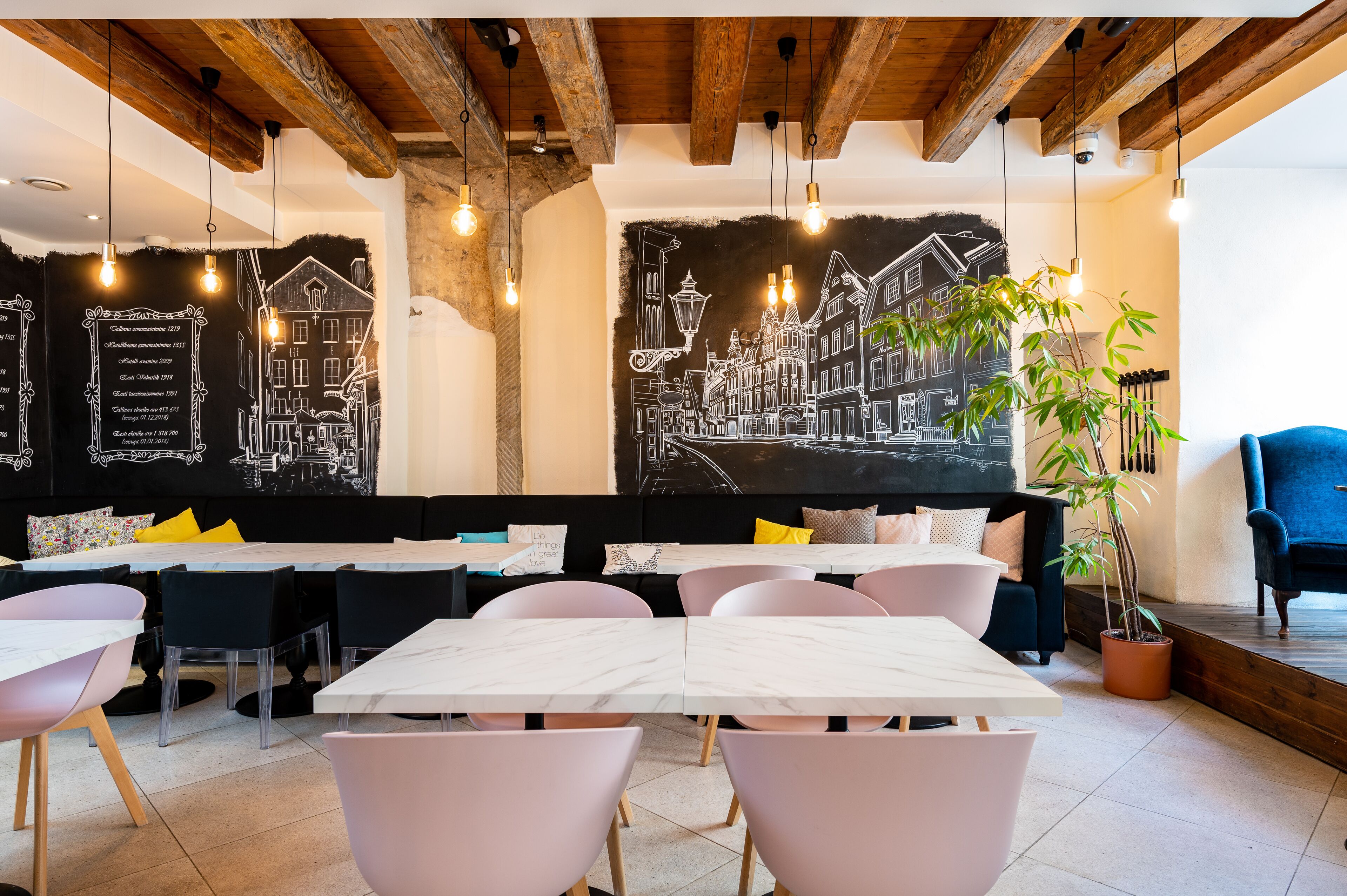 A restaurant with a blackboard menu, wooden ceiling beams, and a large mural of a cityscape.