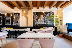 Un restaurant avec un menu écrit à la craie sur un tableau noir, des poutres en bois au plafond et une grande fresque représentant un paysage urbain.