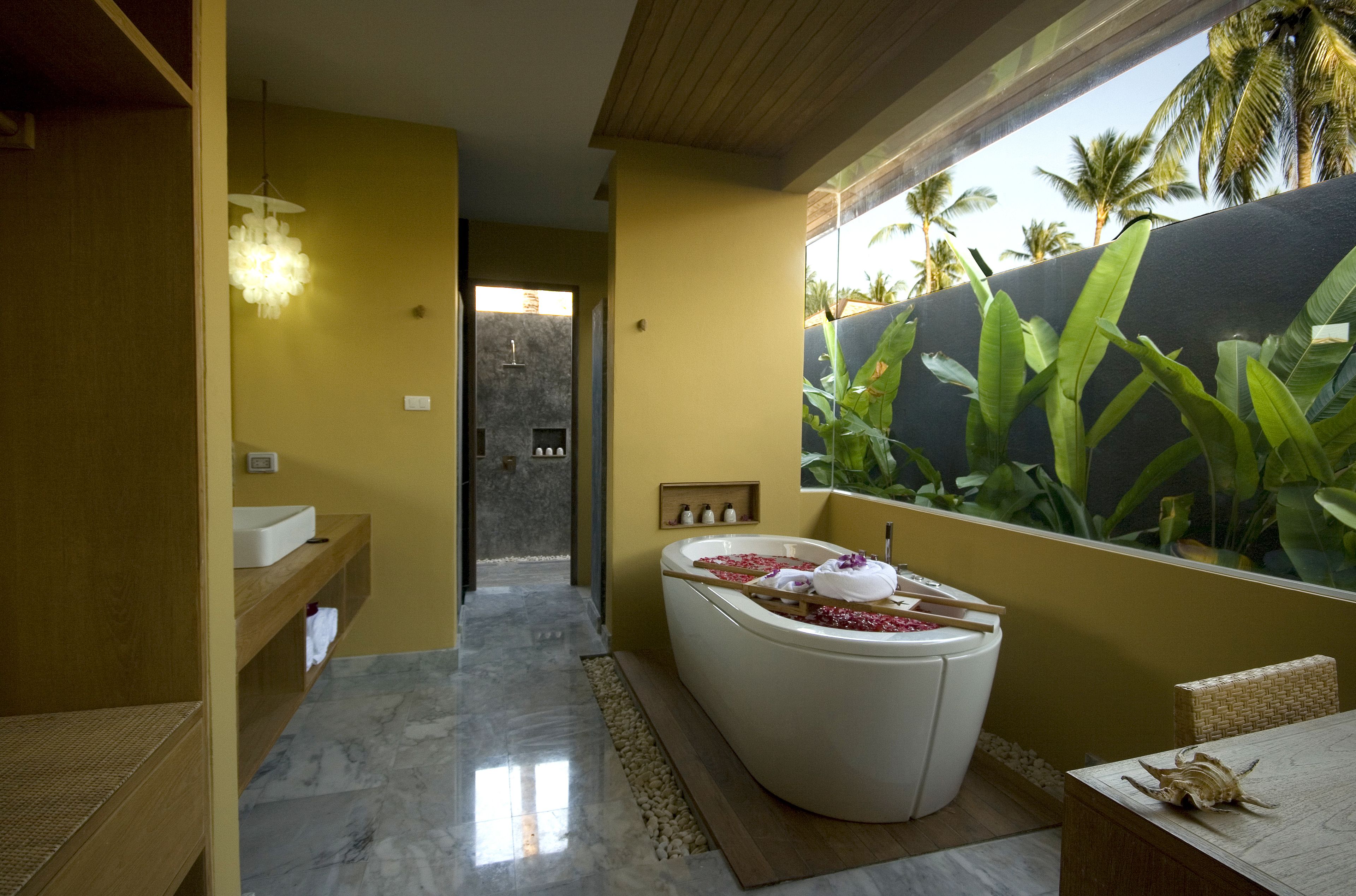 Un baño con bañera, un banco de madera, un lavamanos y zona de ducha.