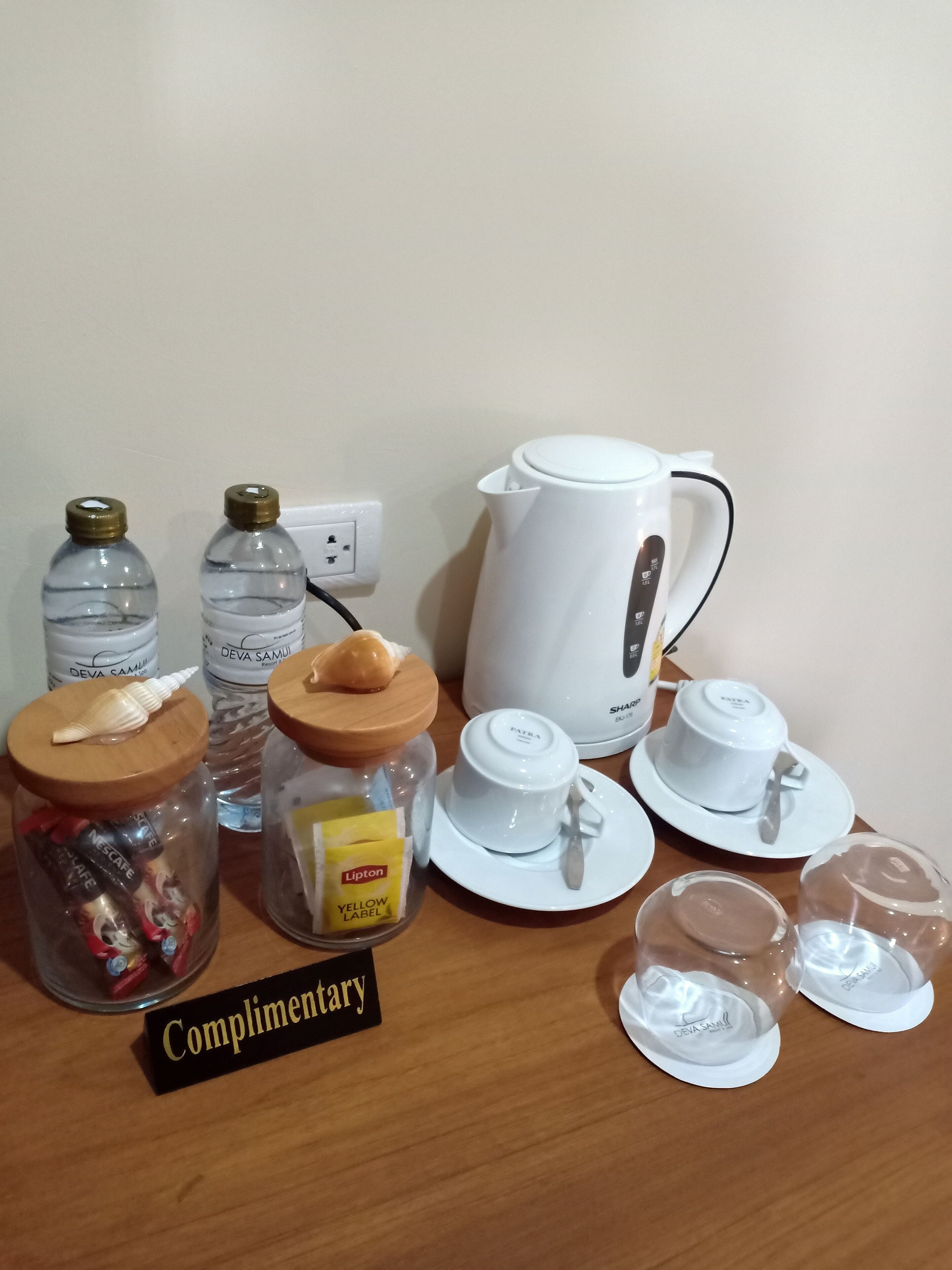 A table with a coffee maker, teapot, cups, and jars labeled "Complimentary".
