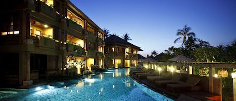 A hotel with a swimming pool, multiple balconies, and outdoor seating areas.