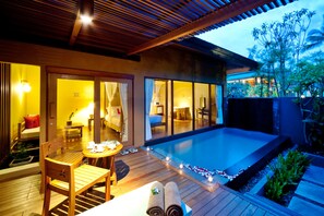 A modern hotel with a swimming pool, wooden deck, and indoor/outdoor seating areas.