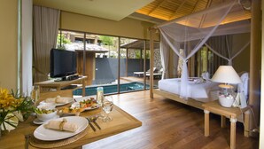 Une pièce spacieuse avec un grand lit, une télévision, une table à manger avec de la nourriture et des boissons, et une vue sur une piscine et un jardin.