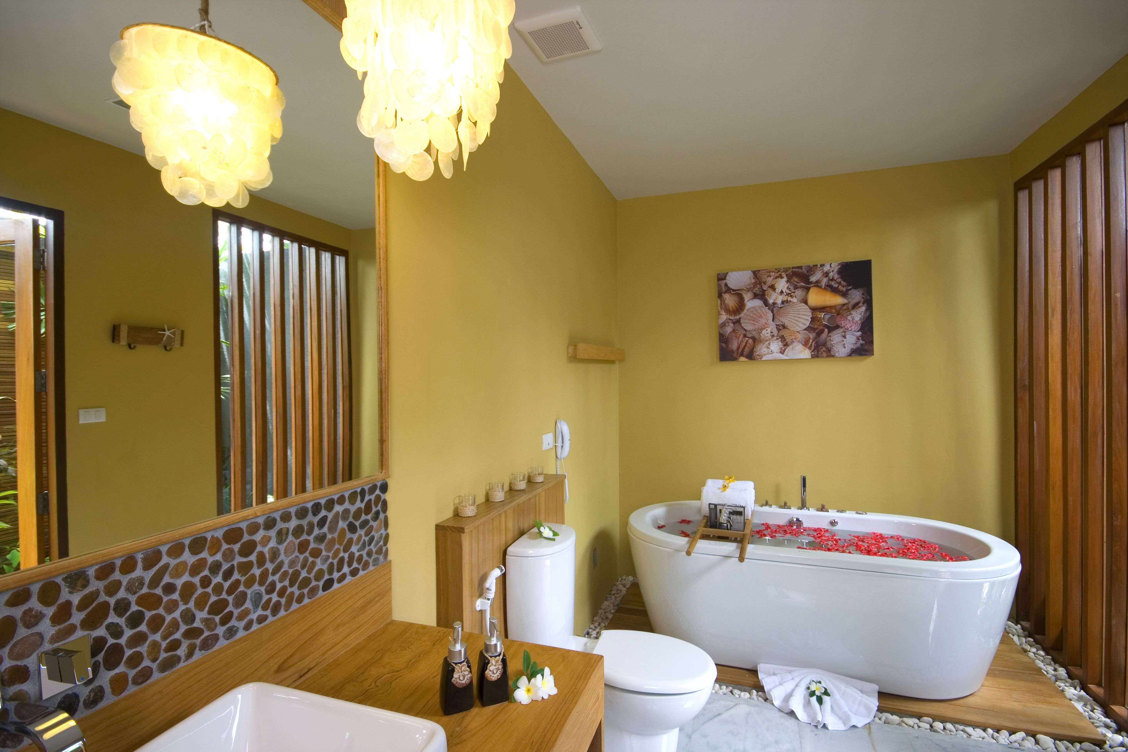 Un baño con una bañera llena de flores rojas, un tocador de madera y un espejo grande.