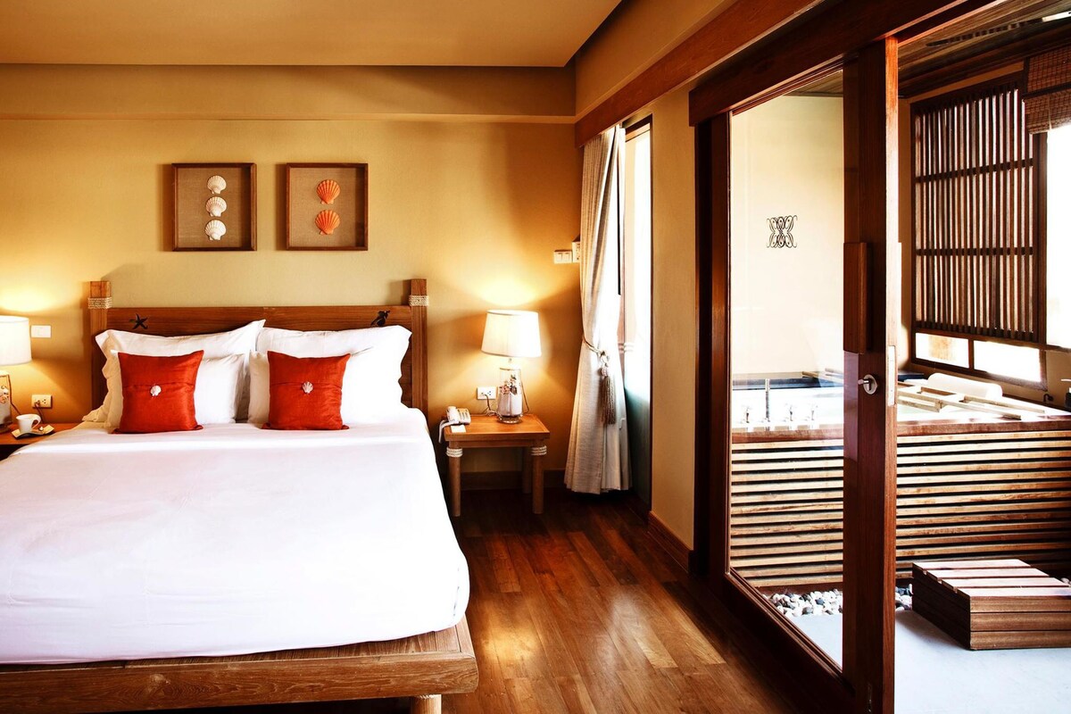 Una habitación de hotel con una cama de madera, mesitas de noche y una vista a través de un celosía japonesa.