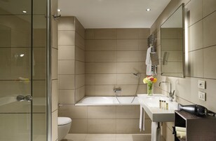 Un bagno moderno con cabina doccia in vetro, una vasca da bagno, un lavabo con articoli da toilette e uno specchio.