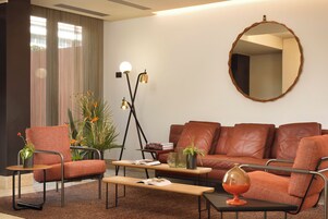 A modern living room with a brown leather sofa, a wooden coffee table, and a round mirror on the wall.