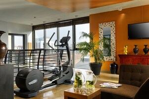 Una palestra moderna con attrezzi da palestra, un'ampia finestra e un'area relax con tavolino.