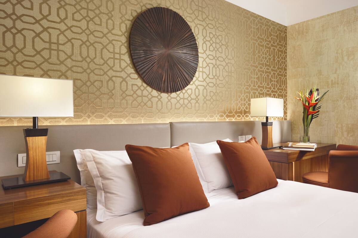 A hotel room with a bed, two nightstands, a desk, and a chair.