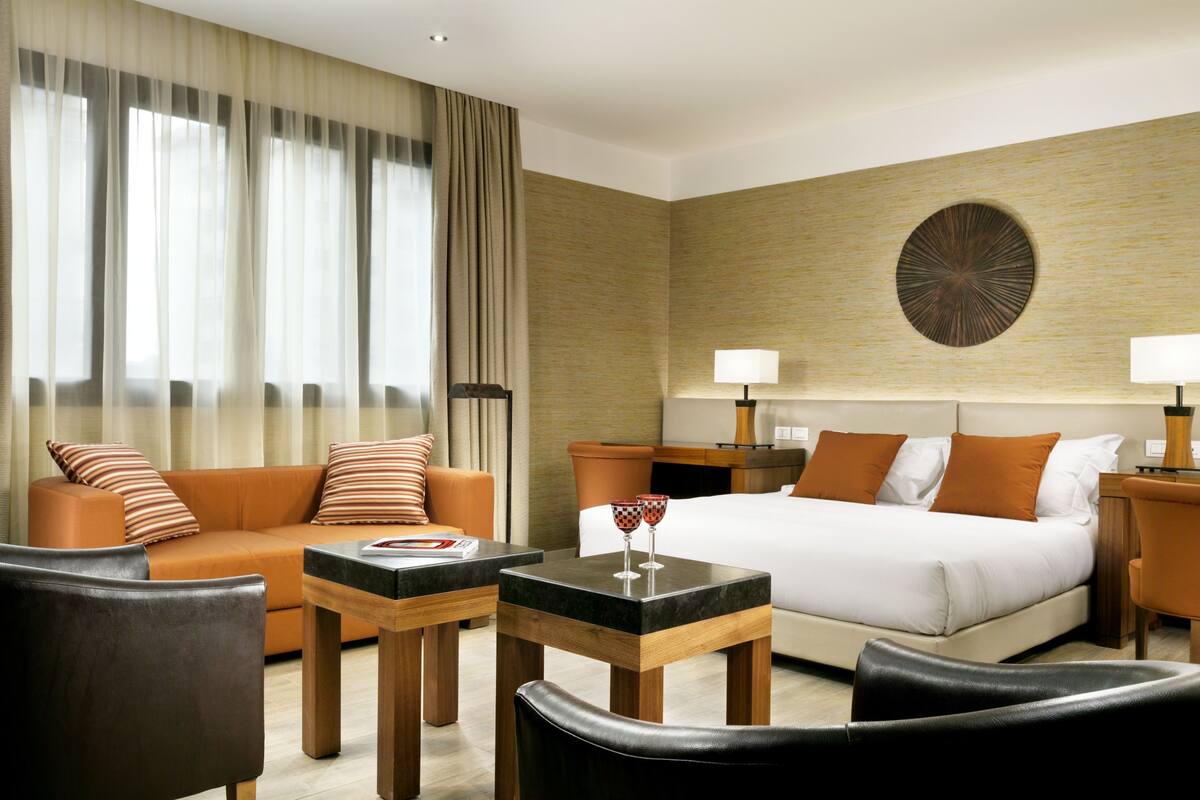 A hotel room with a bed, a sofa, a coffee table, and a desk.