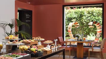Buffet com diversos alimentos e área de recepção com aviso indicando quartos e sanitários sem roupa.