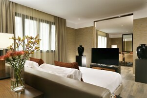 Una camera d'albergo con un letto, una TV, un vaso con fiori e uno specchio.