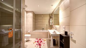 A modern bathroom with a glass shower enclosure, a bathtub, and a sink with a mirror.
