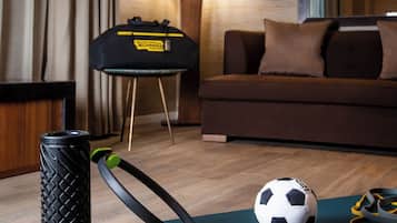 Habitación de hotel con una colchoneta azul para ejercicio, una pesa rusa negra, una pelota de fútbol y una colchoneta de yoga.
