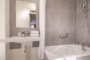 A modern bathroom with a white sink, mirror, and bathtub.