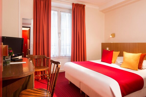 A hotel room with a bed, a desk, a chair, and a television. - Londres Saint-Honoré Hotel (Paris)