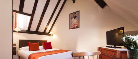 A hotel room with a bed, a television, a wooden chair, and a dresser.