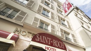 Exterior del hotel Saint Roch, con un letrero llamativo, varios balcones y cielo despejado.