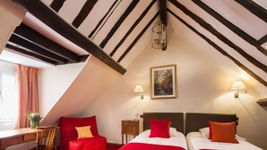Una habitación con dos camas, un escritorio, una silla y un sofá rojo.