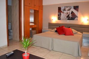 Una habitación de hotel con una cama, una mesita de noche, una maceta roja y un cuadro en la pared.