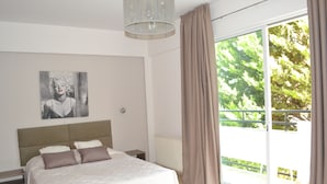 Un dormitorio con una cama grande, un cabecero, una ventana con cortinas y un cuadro en la pared.