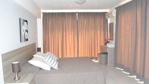 Una habitación de hotel con cama, mesita de noche, lámpara y espejo.