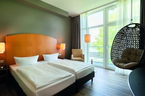 A hotel room with two beds, a hanging chair, and large windows. - Seminaris Sunday Hotel Potsdam Babelsberg (Potsdam)