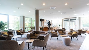 Un hall d’entrée spacieux, doté de mobilier contemporain, d’un bar et de grandes fenêtres laissant entrer la lumière naturelle.