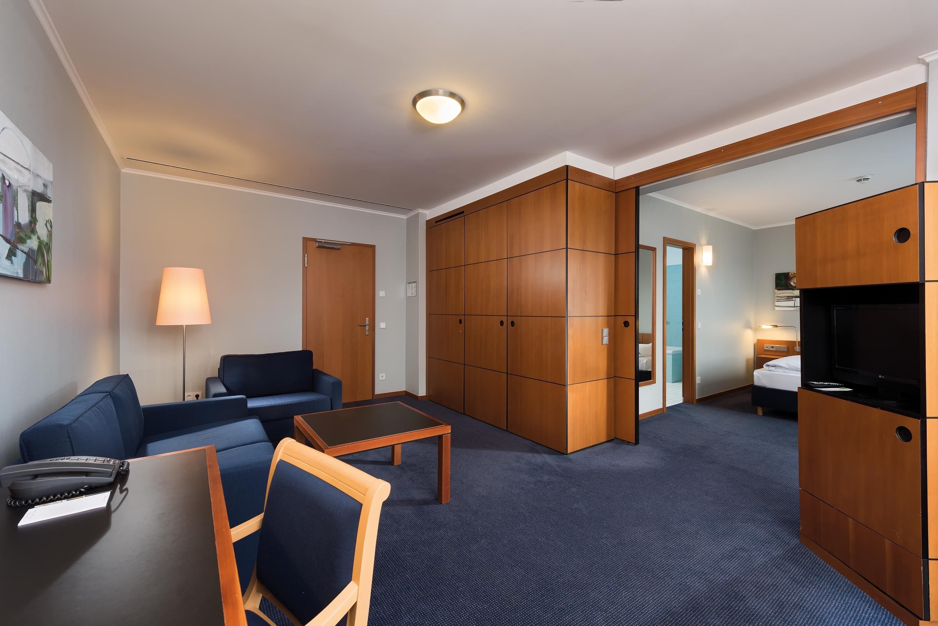 Une chambre d’hôtel avec un canapé, une petite table, une télévision et une armoire.